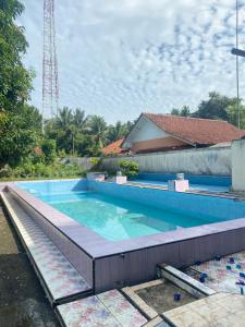 a large swimming pool with blue water in front of a building at Homestay loteng in Madasari
