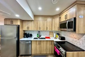 a kitchen with wooden cabinets and a stainless steel refrigerator at Sleek Guest Retreat SW EDM BSMT Suite in Edmonton