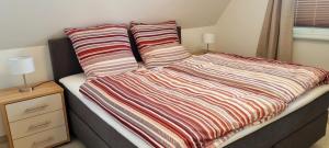 a bed with a striped comforter and two pillows at Reethaus "Dat Lavendelhus" in Zierow +10 photos
