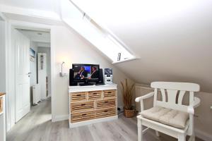 ein Wohnzimmer mit einem TV auf einer Kommode mit einem Stuhl in der Unterkunft Syltrose in Hörnum