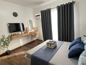a bedroom with a bed with a television and a desk at JeMeCa Suites in Kauswagan