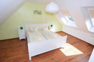 ein Schlafzimmer mit einem weißen Bett mit weißen Kissen in der Unterkunft Wendstraße 10, Ferienhaushälfte in Heiligenhafen