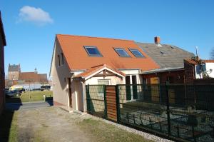 ein Haus mit einem orangefarbenen Dach und einem schwarzen Zaun in der Unterkunft Wendstraße 10, Ferienhaushälfte in Heiligenhafen