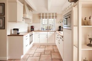 eine Küche mit weißen Schränken und einem Fliesenboden in der Unterkunft Reethüs Maj - links in Utersum