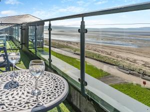 een tafel met een wijnglas op een balkon met uitzicht op het strand bij Beachview in Llanelli