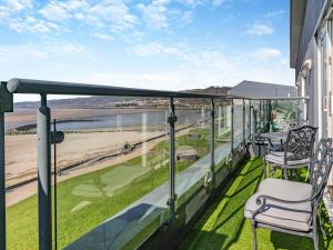 een balkon met stoelen en uitzicht op het strand bij Beachview in Llanelli +17 foto's