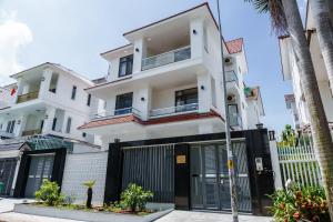 a white house with a black gate and palm trees at HomyPlus Apartment in Ho Chi Minh City