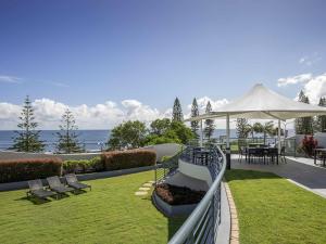 een patio met een witte parasol en een tafel en stoelen bij Mantra Mooloolaba Beach in Mooloolaba