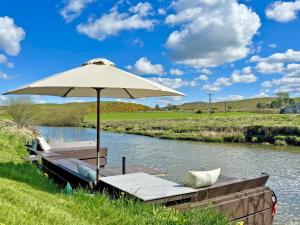 an umbrella sitting on a boat in a river at Harperfield Chalet in Lanark