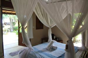 een slaapkamer met een hemelbed en witte gordijnen bij Villa Selina in Tejakula +126 foto's
