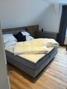 a bed sitting in a bedroom with a wooden floor at Wurmbergblick Ferienwohnung in Braunlage +3 photos