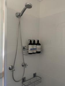 a shower with three bottles on a shelf in a bathroom at Frangipani Studio PET FRIENDLY!!! in Ulladulla