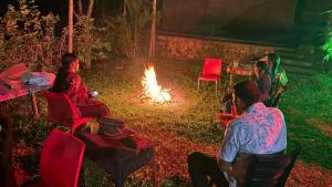 a group of people sitting around a fire at Pepper and Clove Enclave in Puliyara