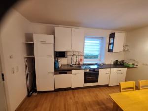 a small kitchen with white cabinets and a sink at Familienwohnung Emprechting in Emprechting