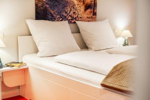 a bed with white sheets and pillows in a room at FöhrEuch 2 in Borgsum +12 photos