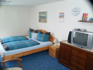a bedroom with a bed and a tv on a dresser at Haus Franziska in Leck