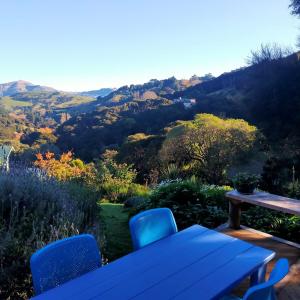 a table and chairs on a deck with a view of a mountain at Delightful Dolphin 'Lodge' in Akaroa
