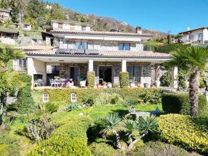 een huis op een heuvel met palmbomen en struiken bij Stay near Lake with Panoramic Views in Oggebbio