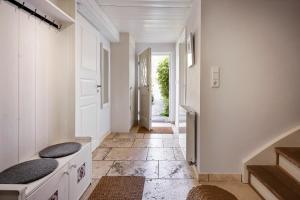 een hal met witte muren en een trap met een deur bij Haus Augenblick in Utersum