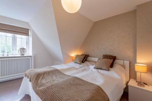a bedroom with a bed with white sheets and a window at Landhaus Meta in Wrixum
