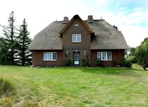 una casa con tetto di paglia su un prato di Hausteil Tornerose a Witsum