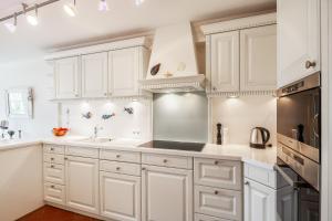 una cucina con mobili bianchi e un lavandino di Hausteil Tornerose a Witsum