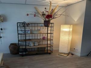 een kamer met een plank met een vaas met bloemen en een lamp bij Alluring Apartment in Bergen with Terrace, Garden and BBQ in Bergen