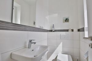 a white bathroom with a sink and a mirror at City Marina, CM20a in Cuxhaven