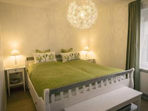 a bedroom with a green bed with a chandelier at Ferienhaus Sommerwiese - ABC327 in Klein Warin