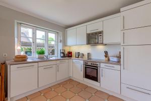 a white kitchen with white cabinets and appliances at Reetdachhaus Hedehusum in Hedehusum