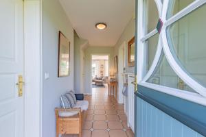 a hallway with a blue door and a window at Reetdachhaus Hedehusum in Hedehusum
