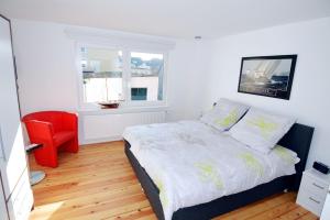 a bedroom with a bed and a red chair at Fischers Fritz - Brückstr 32 in Heiligenhafen