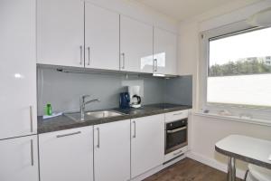 a white kitchen with a sink and a window at Luv & Lee, Whg 3 in Westerland