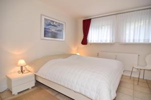 a bedroom with a white bed and a table and window at Luv & Lee, Whg 3 in Westerland