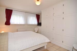 a white bedroom with a white bed and a window at Luv & Lee, Whg 3 in Westerland +7 photos