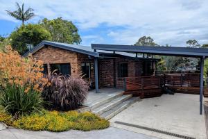 a brick house with a black roof and a porch at Mollymook Den Coastal Retreat - Walk to Beach & Town in Mollymook