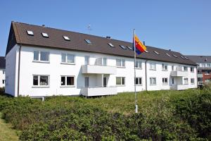 een groot wit gebouw met een vlag ervoor bij Strandmuschel in Hörnum