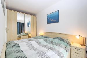 een slaapkamer met een bed, een ladekast en een spiegel bij Strandmuschel in Hörnum