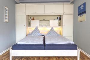 Bett in einem Zimmer mit einem weißen Schrank in der Unterkunft Thulboden 2a in Heiligenhafen