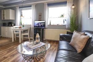 ein Wohnzimmer mit einer schwarzen Ledercouch und einem Tisch in der Unterkunft Thulboden 2a in Heiligenhafen