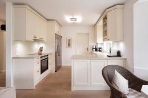 a white kitchen with white cabinets and a table at Deichgraf in Dunsum +15 photos