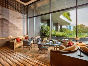 a restaurant with tables and chairs and large windows at Pullman Hai Phong Grand Hotel in Hai Phong