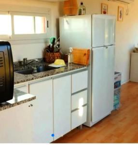 a kitchen with white cabinets and a white refrigerator at Pasos del Dique in Cortaderas +43 photos