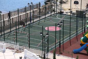 a tennis court next to the ocean with a playground at Ribera Resort&SPA in Yevpatoriya