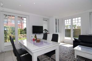 a white dining room with a white table and chairs at Maybachstraße 22 in Westerland