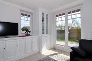 a living room with a flat screen tv and windows at Maybachstraße 22 in Westerland