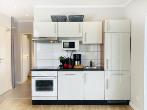 a kitchen with white cabinets and a white refrigerator at Apartment Priwall Teichhof Fehmarn in Wenkendorf