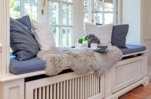 a bench with pillows and a fur blanket at Ferienhaus Hideaway in Kampen