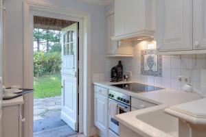 a white kitchen with a sink and a stove at Ferienhaus Hideaway in Kampen +27 photos