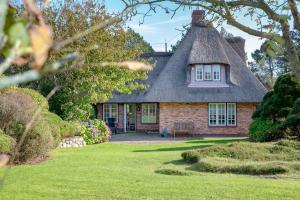 a small brick house with a thatched roof at Ferienhaus Hideaway in Kampen